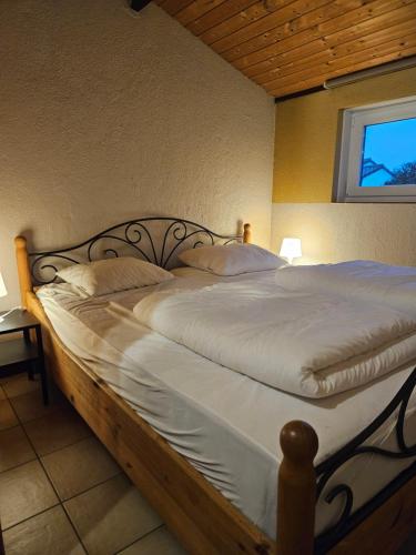 uma cama com lençóis brancos e almofadas num quarto em Duinenhuis Zeepolder 28 em De Haan