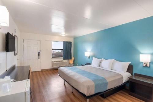een slaapkamer met een groot bed met een blauwe muur bij Motel 6 in Colorado Springs