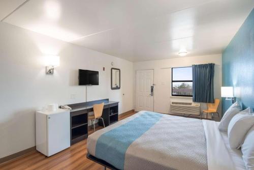 a hotel room with a bed and a desk and a television at Motel 6 in Colorado Springs