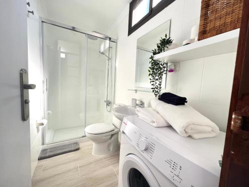 a white bathroom with a washing machine and a toilet at Apartamento Bungamerica 2 bedrooms Costa Adeje in Playa de las Americas