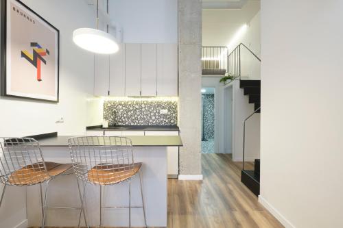 een keuken met witte kasten en een aanrecht met stoelen bij Acacias Apartments - City Centre in Madrid
