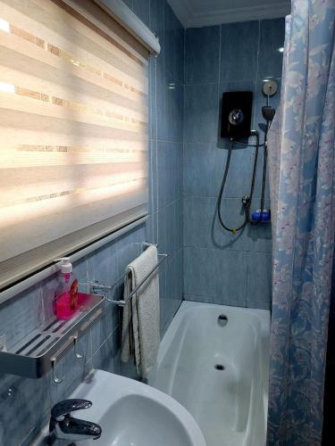 a bathroom with a tub and a sink and a window at GHouse in Adentan