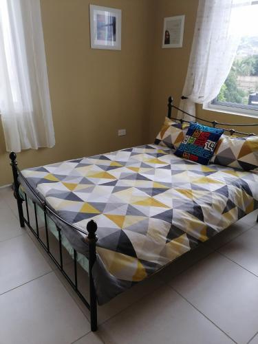 una camera con un letto con un piumone a scacchi di L & J Apartments a Dawhwenya