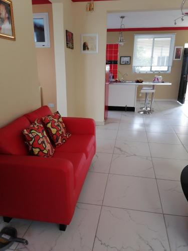 a living room with a red couch and a kitchen at L & J Apartments in Dawhwenya