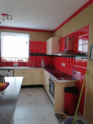 a kitchen with red tiles on the walls at L & J Apartments in Dawhwenya