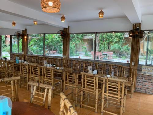 a restaurant with wooden tables and chairs and large windows at Ham Rong Bungalow in Xuân Sơn