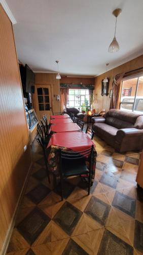 a room with a long table with chairs and a couch at Hostal familiar traveltour El Campesino in Puerto Natales