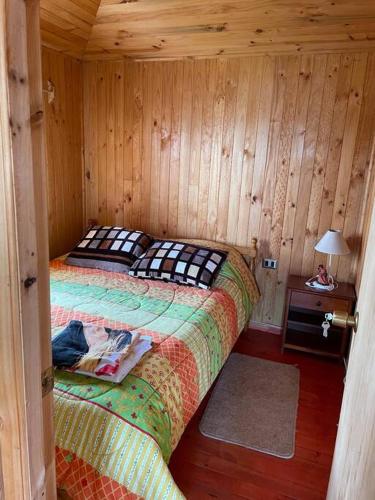 ein Schlafzimmer mit einem Bett in einer Holzhütte in der Unterkunft Cabaña 4 personas en Calen Rural, Chiloé in Dalcahue