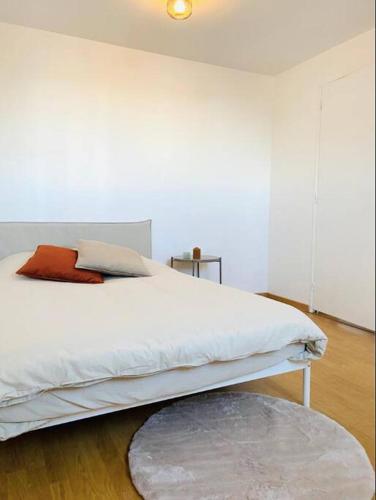 une chambre avec un lit blanc avec un oreiller rouge dans l'établissement Appartement Duplex Cosy, au Havre