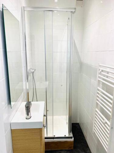 La salle de bains est pourvue d'une douche et d'un lavabo blanc. dans l'établissement Appartement Duplex Cosy, au Havre