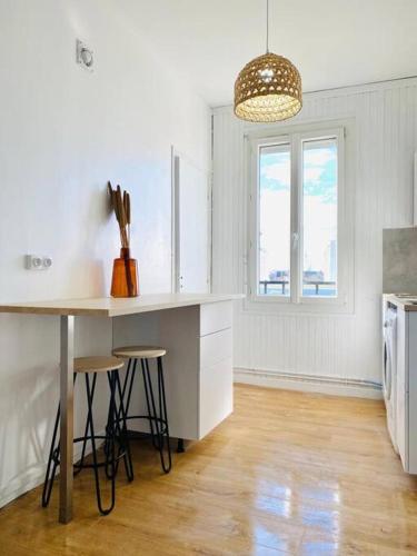 une cuisine avec une table et des tabourets ainsi qu'une fenêtre dans l'établissement Appartement Duplex Cosy, au Havre