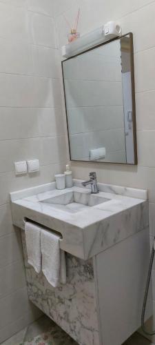 W łazience znajduje się biała umywalka i lustro. w obiekcie Essaouira Cool apartments w mieście As-Suwajra