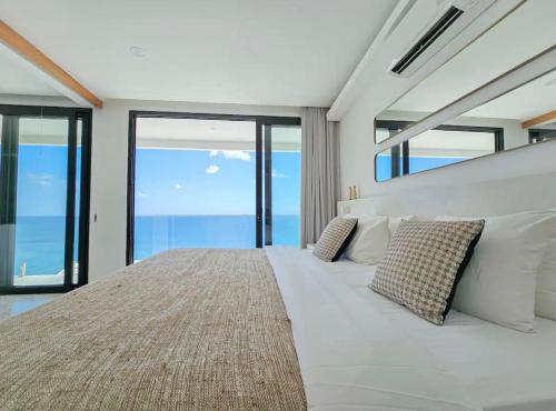 a bedroom with a large white bed with large windows at Villa Endless - Two Bedroom Family Suite - Beachfront Luxury - Bingin Beach in Uluwatu