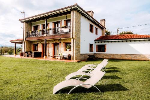 un grupo de sillones blancos en el césped frente a una casa en Villa Tiviti en Oviedo