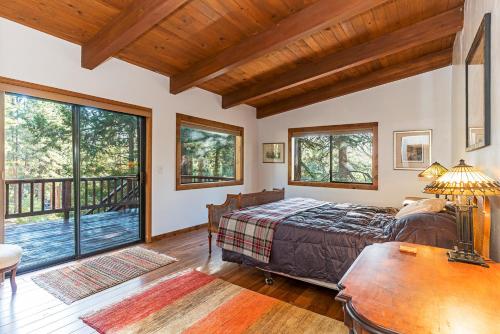 a bedroom with a bed and a table and windows at 451 First Green Dr - Mountain Home in Incline Village