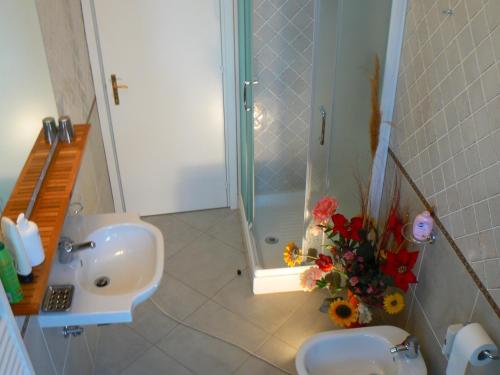 a bathroom with a sink and a shower and flowers at B&B Aquilone in Urbino
