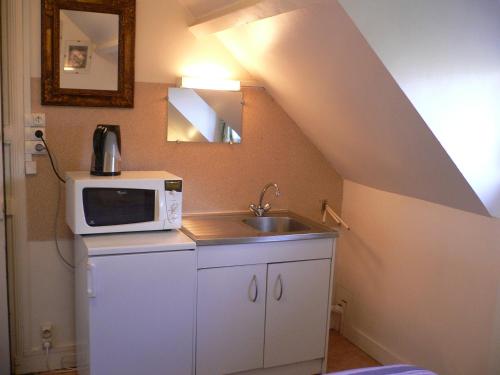 une petite cuisine avec un micro-ondes et un évier dans l'établissement Invitation au voyage, à Le Mesnil-Esnard