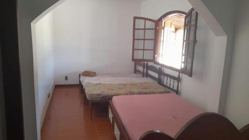 um pequeno quarto com 2 camas e uma janela em Sítio morada nova em Contagem