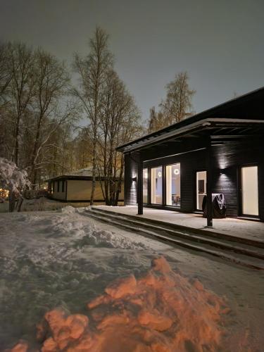 un edificio con nieve en el suelo delante de él en Private Villa, 127m2, 3 br, sauna, fast wifi en Rovaniemi