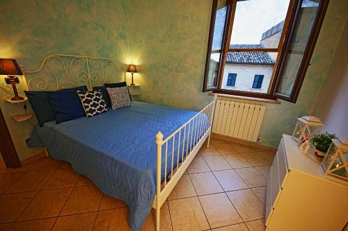 een slaapkamer met een bed met blauwe lakens en een raam bij Dimora San Martino in Offida