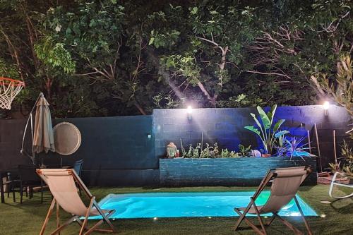 a swimming pool at night with two chairs and a fence at Maisonnette climatisée avec piscine & Spa in Marseille