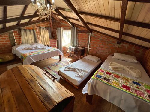 a attic room with two beds and a table at Pousada Tarumã challes 01 in Bonito