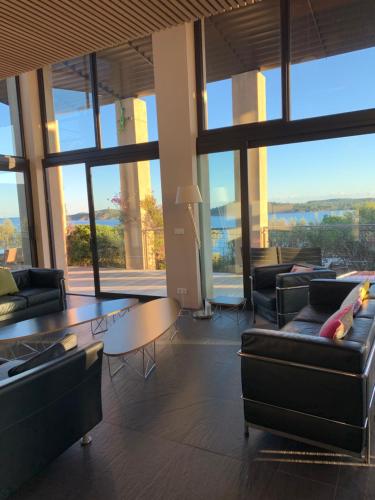 a living room with couches and a table and large windows at Villa Libecciu in Sainte-Lucie de Porto-Vecchio