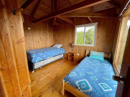 1 dormitorio con 2 camas en una cabaña de madera en Cabañas Kalfvgen, en Valdivia