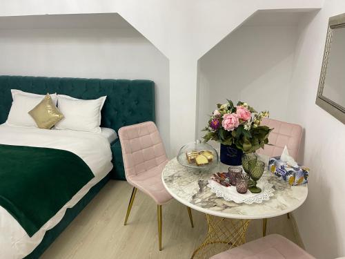 um pequeno quarto com uma cama e uma mesa com flores em Vila Zoe BucharestAirport&Therme&Parking Otopeni em Otopeni