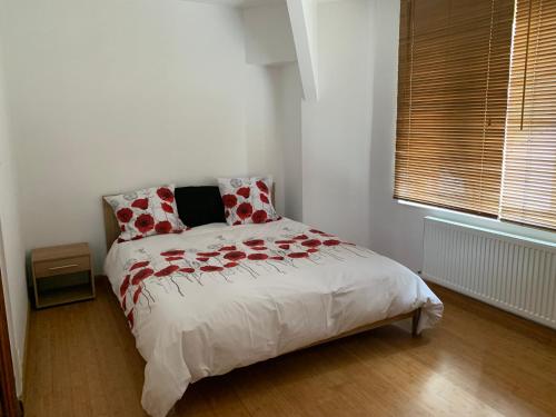 Un dormitorio con una cama con flores rojas. en Appartement vue sur Meuse en Namur
