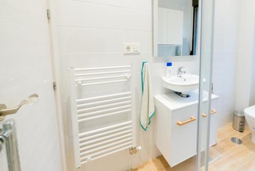 uma casa de banho branca com um lavatório e um espelho em TrendyHomes Granada - moderno apartamento a 15 minutos del centro em Granada