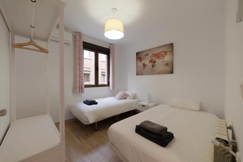 TrendyHomes Granada - moderno apartamento a 15 minutos del centro في غرناطة: غرفة بيضاء بسريرين ونافذة