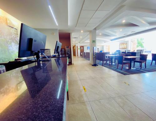 a lobby with a restaurant with tables and chairs at La Quinta by Wyndham Aguascalientes in Aguascalientes