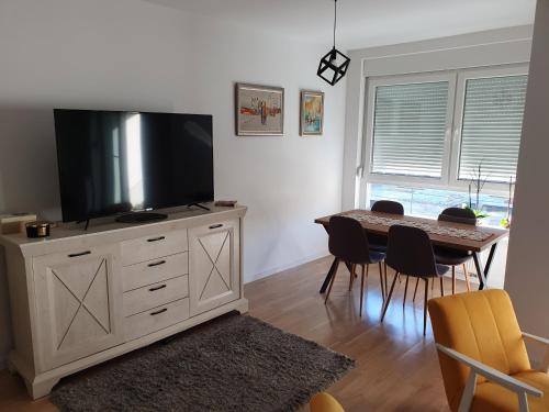 a living room with a television on a dresser with a table at Apartment Noa in Tuzla