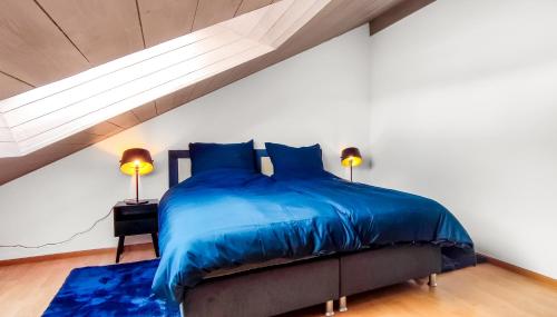 a bedroom with a bed with blue comforter and two lamps at Stylish loft with balcony, quiet and spacious in Unterschleißheim