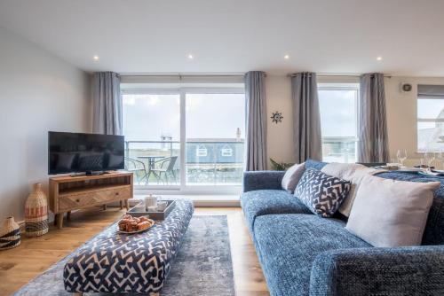 Una sala de estar con un sofá azul y un televisor en Beautiful Central Tenby Apartment with free parking, en Tenby