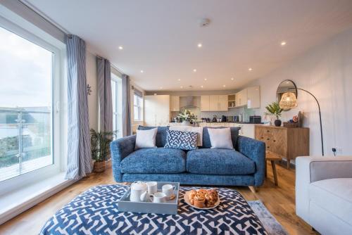 Una sala de estar con un sofá azul y una cocina. en Beautiful Central Tenby Apartment with free parking, en Tenby