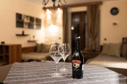 a bottle of beer and two wine glasses on a table at Apartman W Residence in Kopaonik