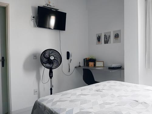 摩基達斯克魯易斯市的住宿－Apartamento Completo A25 Flat Centro，一间卧室配有一张床、一张桌子和风扇