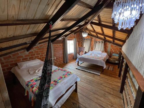a attic room with two beds and a chandelier at Pousada Taruma Challes 02 in Bonito
