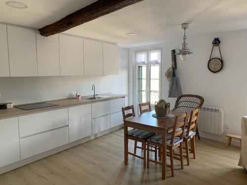 a kitchen with white cabinets and a table and chairs at ISTUA - Etxie La Casa in Bermeo