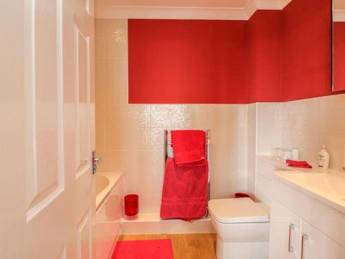 a red bathroom with a toilet and a red towel at Stunning Seaviews - Beach House - Jacuzzi Bath tub in Littlestone-on-Sea