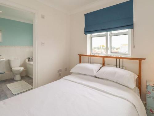 ein Schlafzimmer mit einem großen weißen Bett und einem Fenster in der Unterkunft Stunning Seaviews - Beach House - Jacuzzi Bath tub in Littlestone-on-Sea