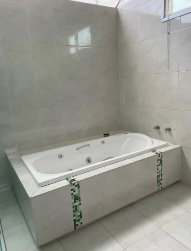 a white bathroom with a tub in a room at Casa Amarela - Sobrado em Brotas in Brotas