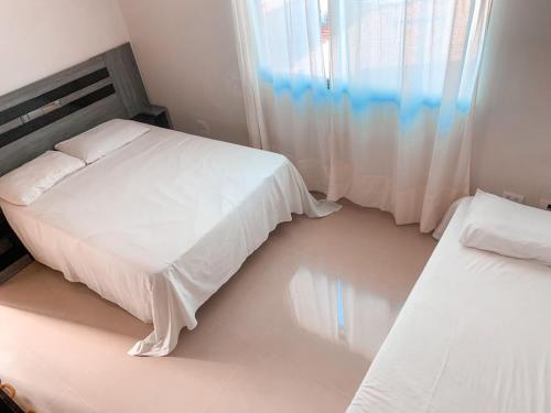 a bedroom with two beds and a window at CASA EM PORTO DE GALINHAS in Porto De Galinhas