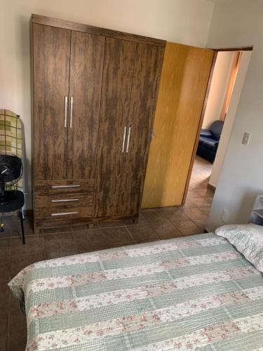 a bedroom with a wooden cabinet and a bed at Apartamento funcional in Varginha