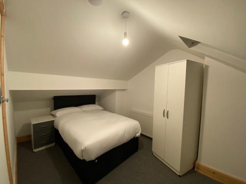 um pequeno quarto com uma cama branca e um armário em Spacious 4BR Close to Digbeth em Birmingham