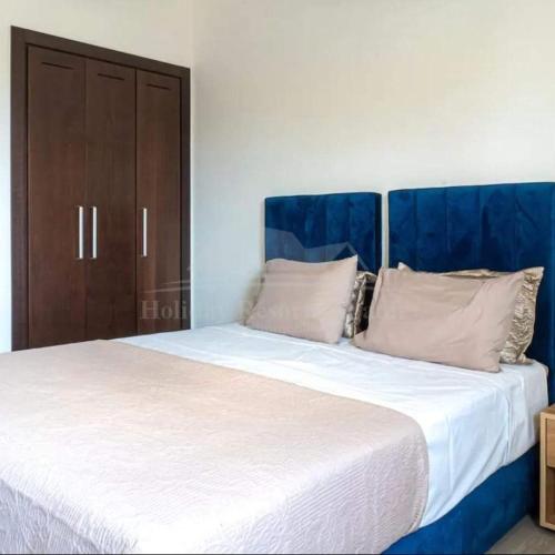 1 dormitorio con 1 cama blanca grande y armario de madera en Studio vue golf Taghazout Bay Tamourit en Agadir