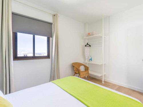 a bedroom with a bed and a window and a chair at Mahostly Apartamento Comillas SE in Arrecife