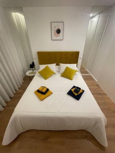 a large white bed with yellow and blue pillows on it at Chez Alexandre - Magnifique Appartement - Ponte de Lima - Wifi Gratuit - Parking Gratuite in Cancinhola